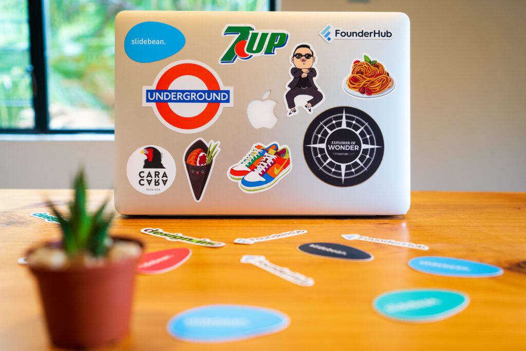 Laptop with stickers of different brand logos on it, sitting on yellow table
