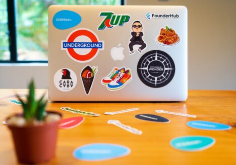 Laptop with stickers of different brand logos on it, sitting on yellow table