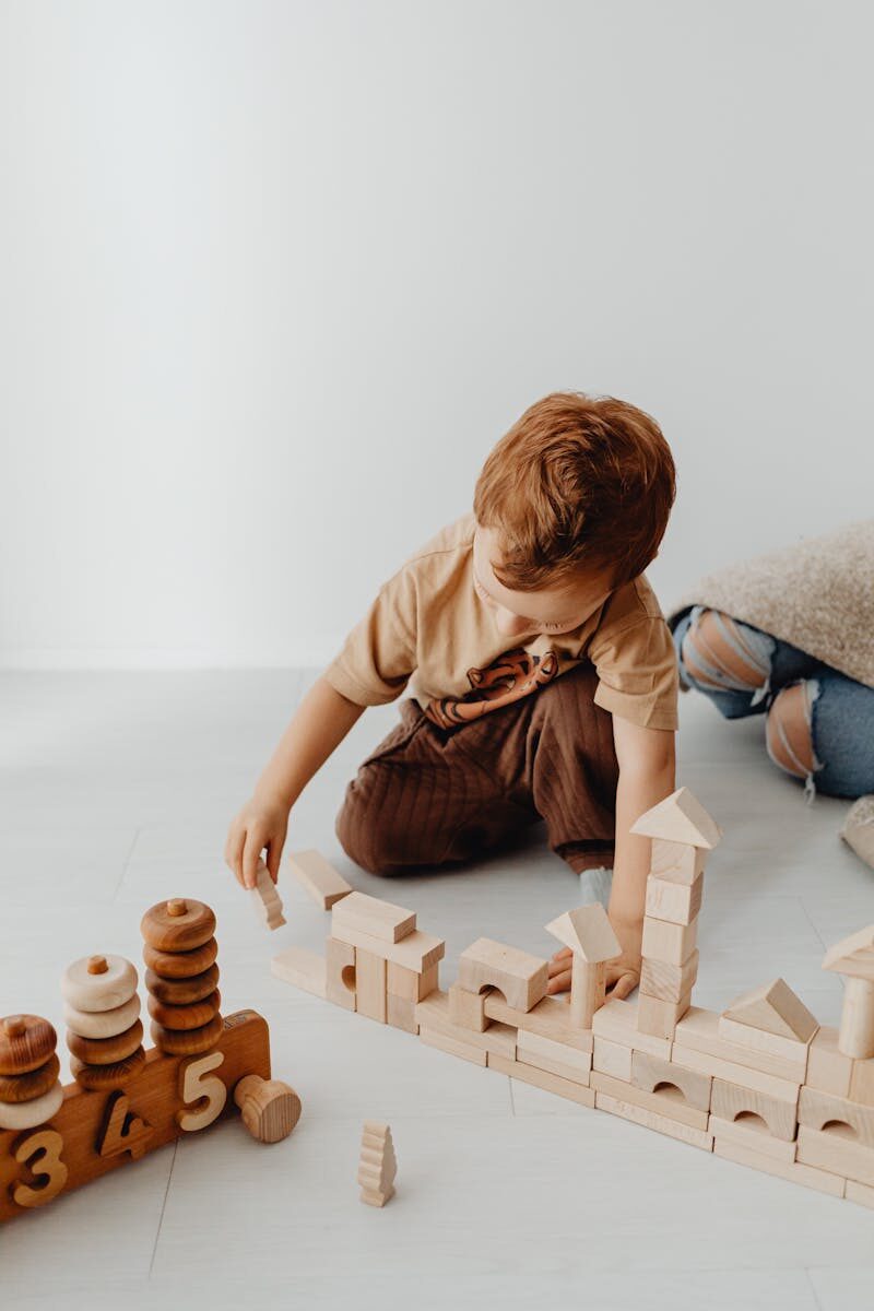 Young boy constructing with wooden building blocks, promoting creativity and play.
